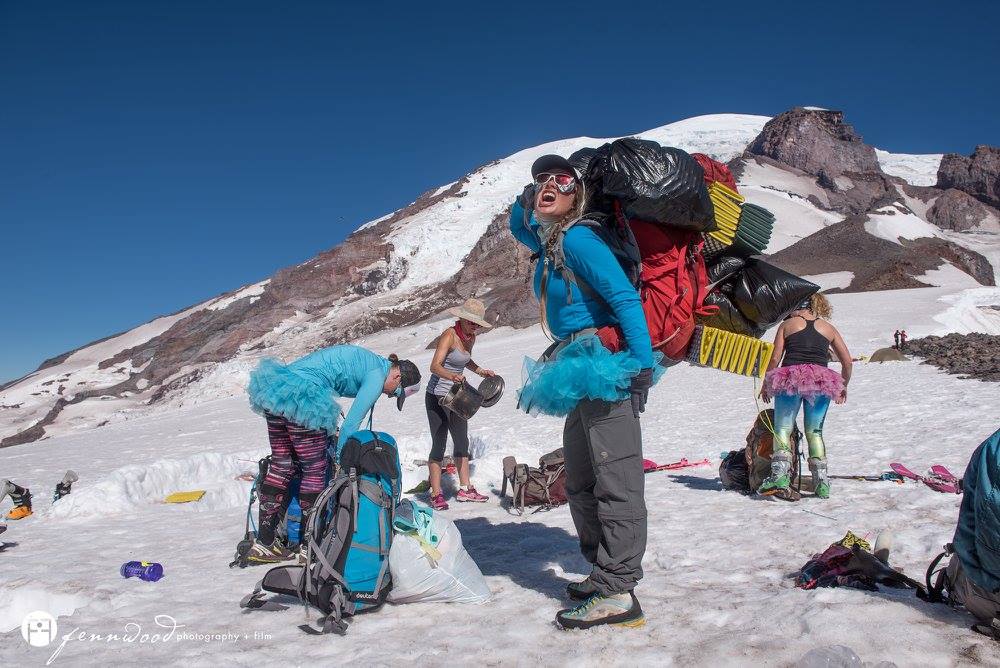 Members of SheJumps clean up camp on Mt. Rainier, carrying blue bags and practicing Leave No Trace principles