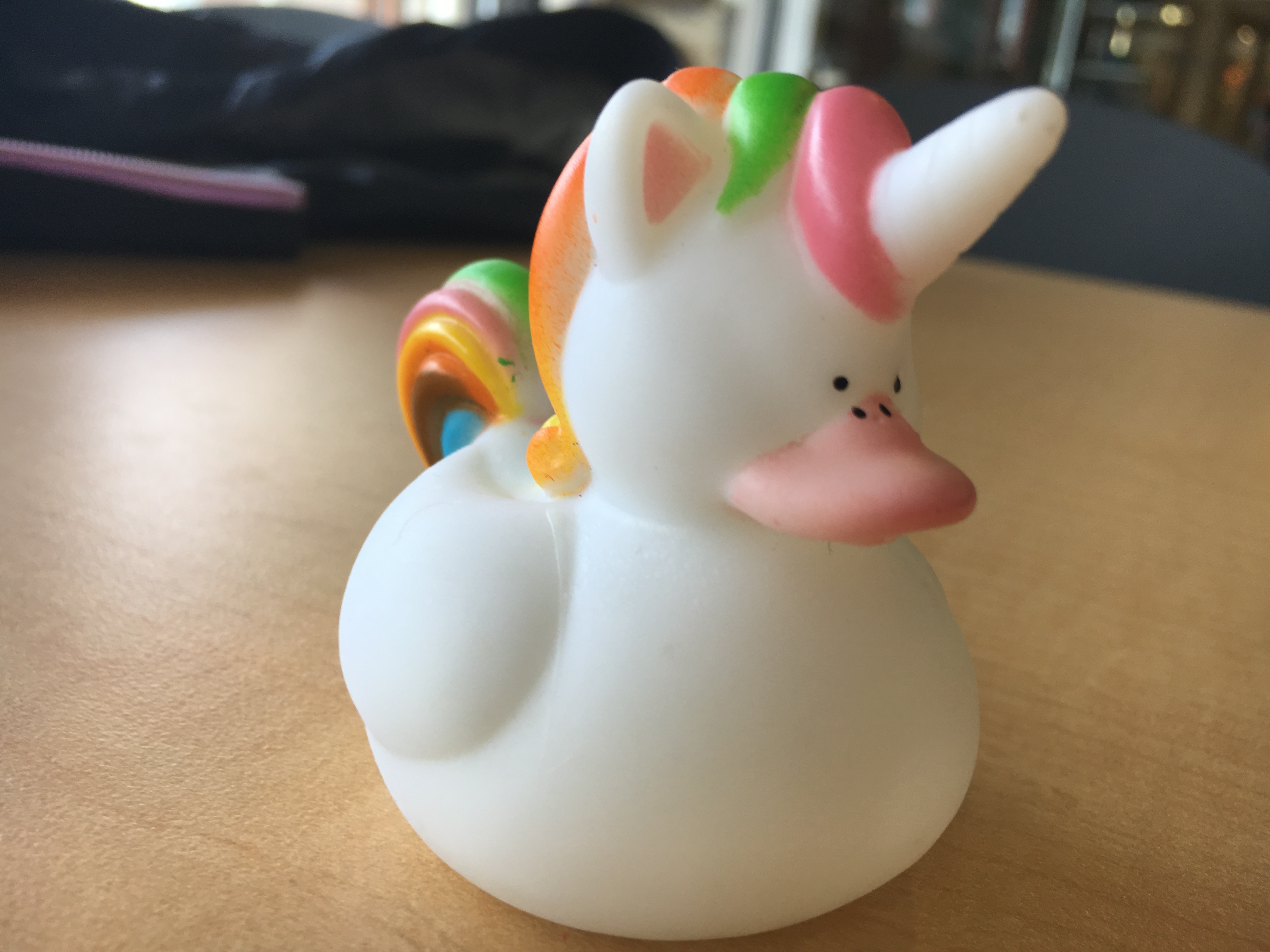 A white, unicorn rubber ducky with a rainbow mane.