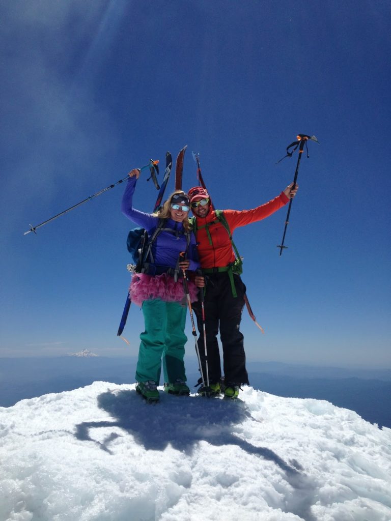 A man and a woman celebrate on the summit of Mt. Adams not realizing their friends are worried at home because they had not followed the sound advice of what to include in a Backcountry Trip Plan.