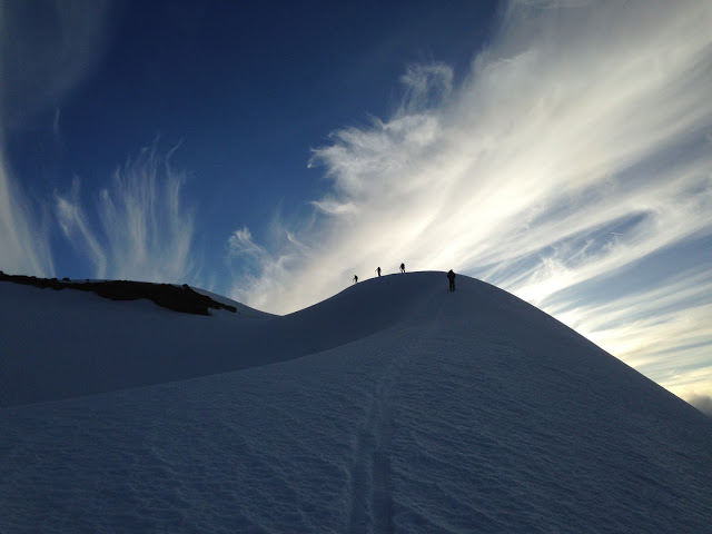 The silhouette of skiers on a dark snowy ridgeline with clouds lit by sunlight in the background to celebrate the Top 10 posts this year.
