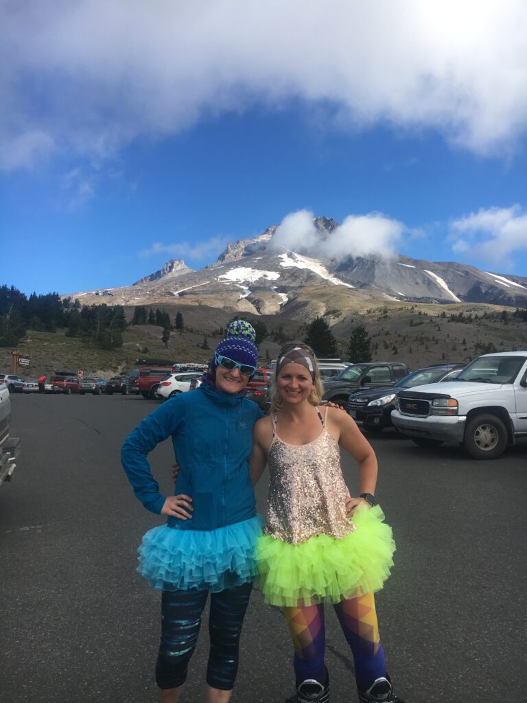 Two women wearing tutus stand in front of Wyeast Peak, Oregon.