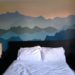 A 9-color mountain mural is painted on a wall, with a bed and two night stands placed in front.